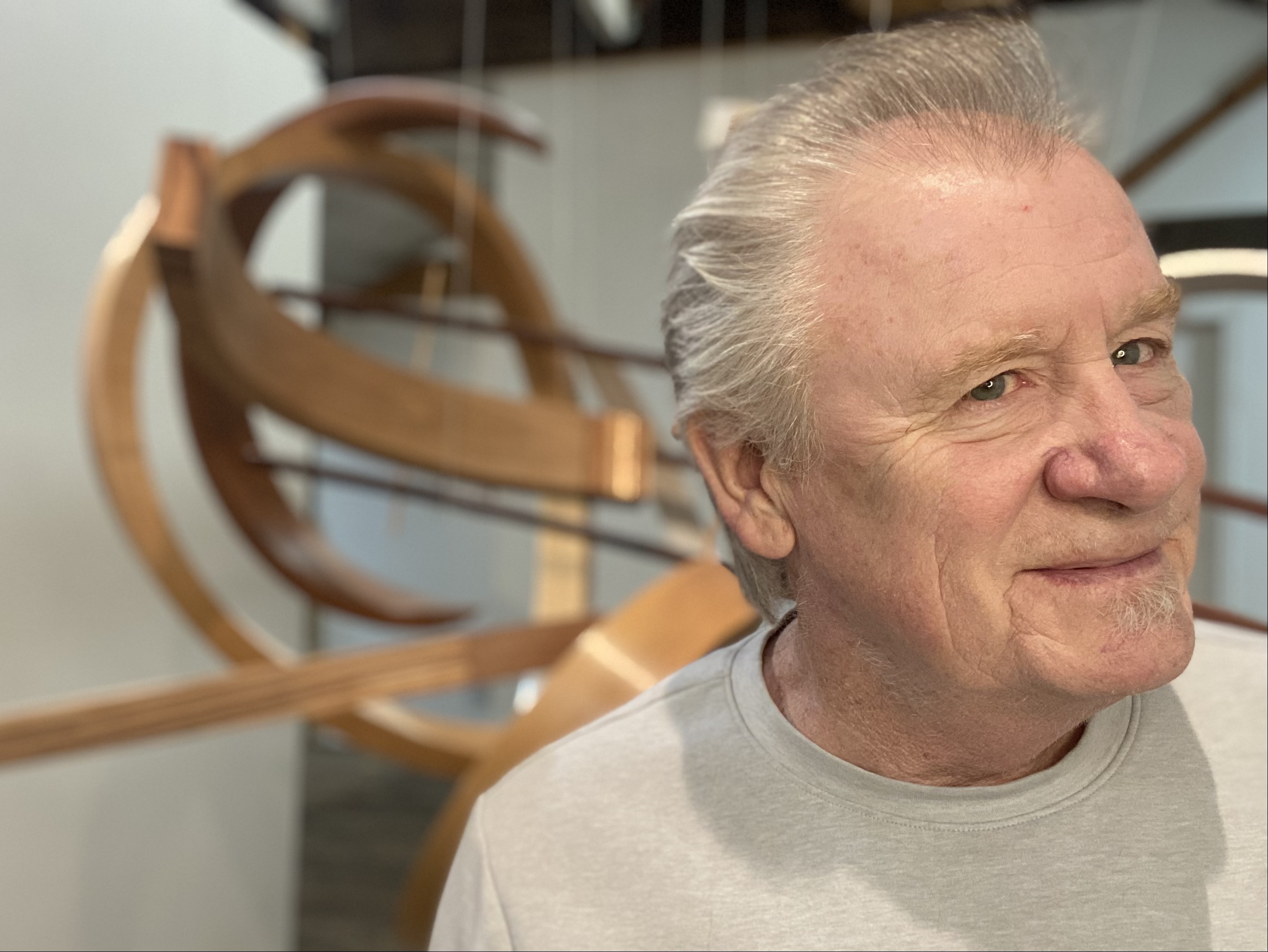 rick maxwell standing by his bent wood sculpture